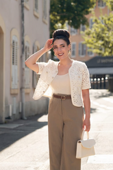 a lady in an openwork white jacket and a pair of brown pants
